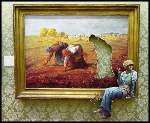 Painting of women working in a field. One has been cut out of the painting and is sitting in the corner of the frame, smoking.