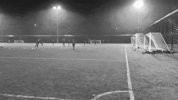 Football pitch with floodlights showing wind and rain.