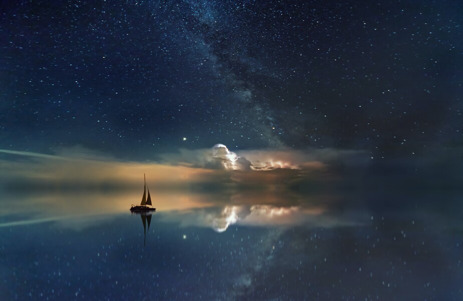 Boat sailing on sea with clouds and stars in the distance