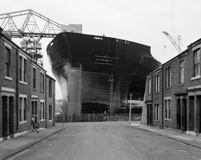 Chris Killip photograph from 'Pride and Fall'. Huge ship at the end of a terrace street.