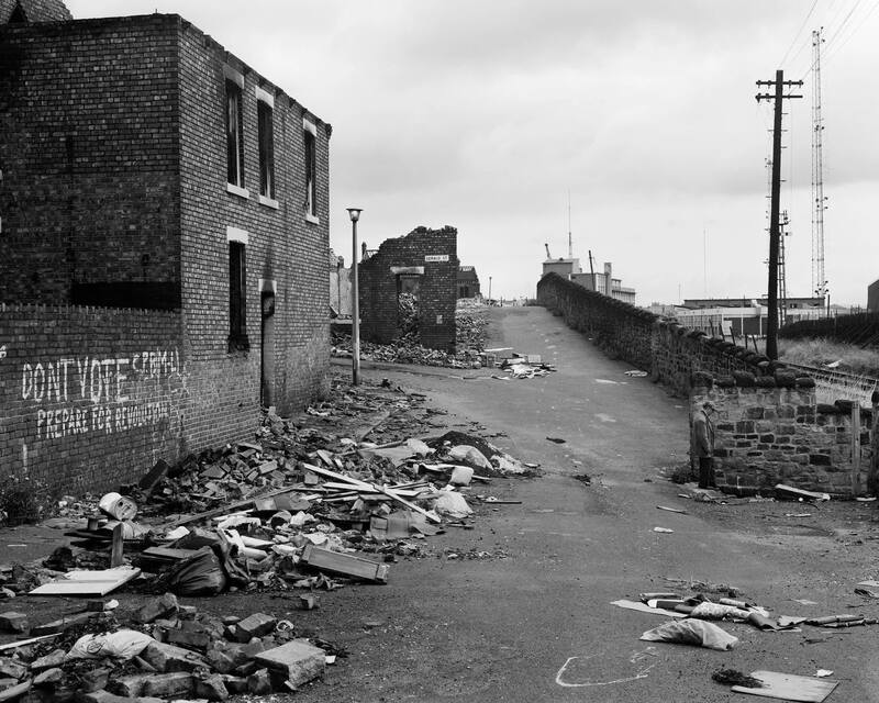 Chris Killip photograph from 'Pride and Fall'. Partly-demolished housing with graffiti saying DON'T VOTE PREPARE FOR REVOLUTION
