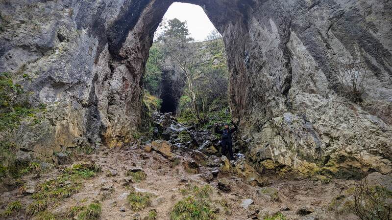Bryan standing underneath a huge limestone arch at Dovedale