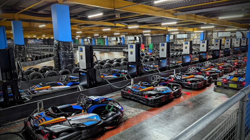 A line of e-karts, charging, next to the racetrack