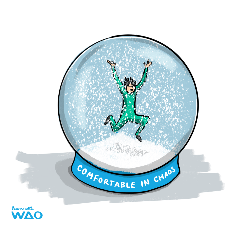  Illustration of an elated person in a checkered green outfit leaping joyfully inside a snow globe with the phrase "COMFORTABLE IN CHAOS" written on the base, accompanied by the "learn with WAO" watermark.