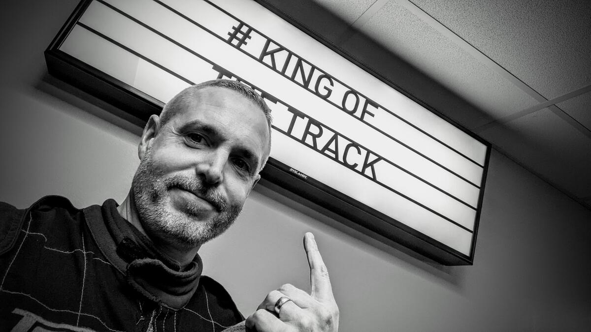 Doug pointing at a sign saying # KING OF THE TRACK