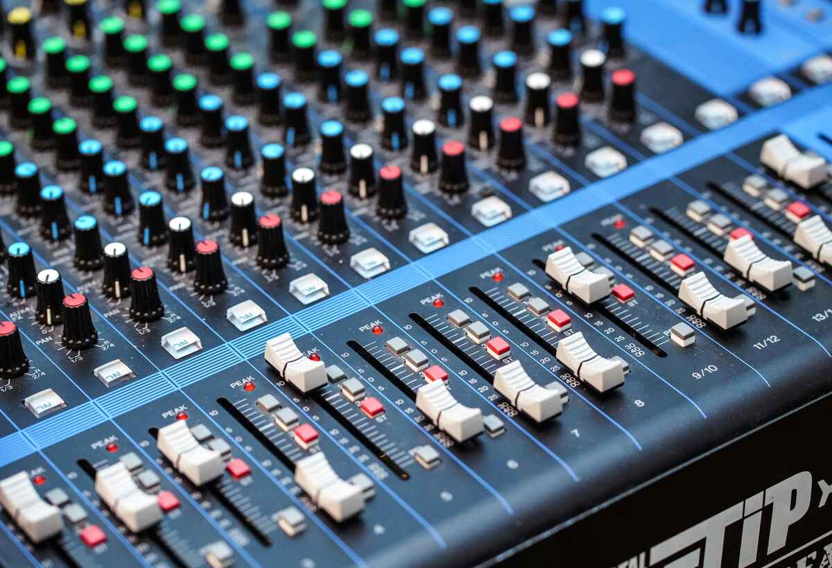  Close-up of an audio mixing console with knobs and faders.