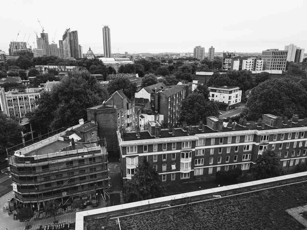 Black-and-white photo of an urban landscape with residential buildings, trees, and high-rises in the background.