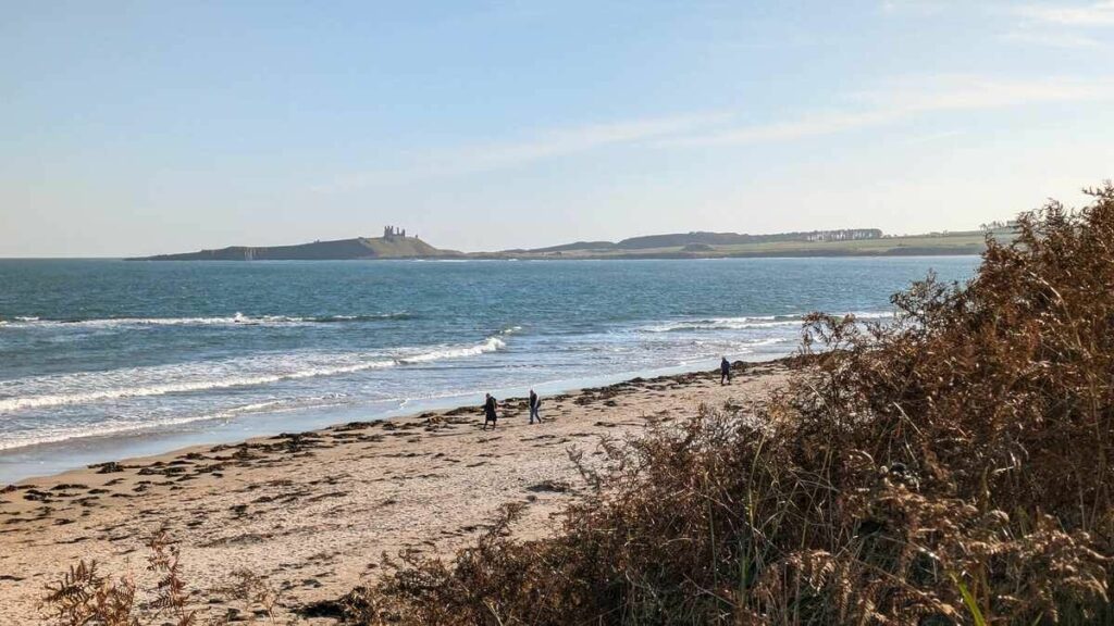 Beach, sea, ruined castle in background 