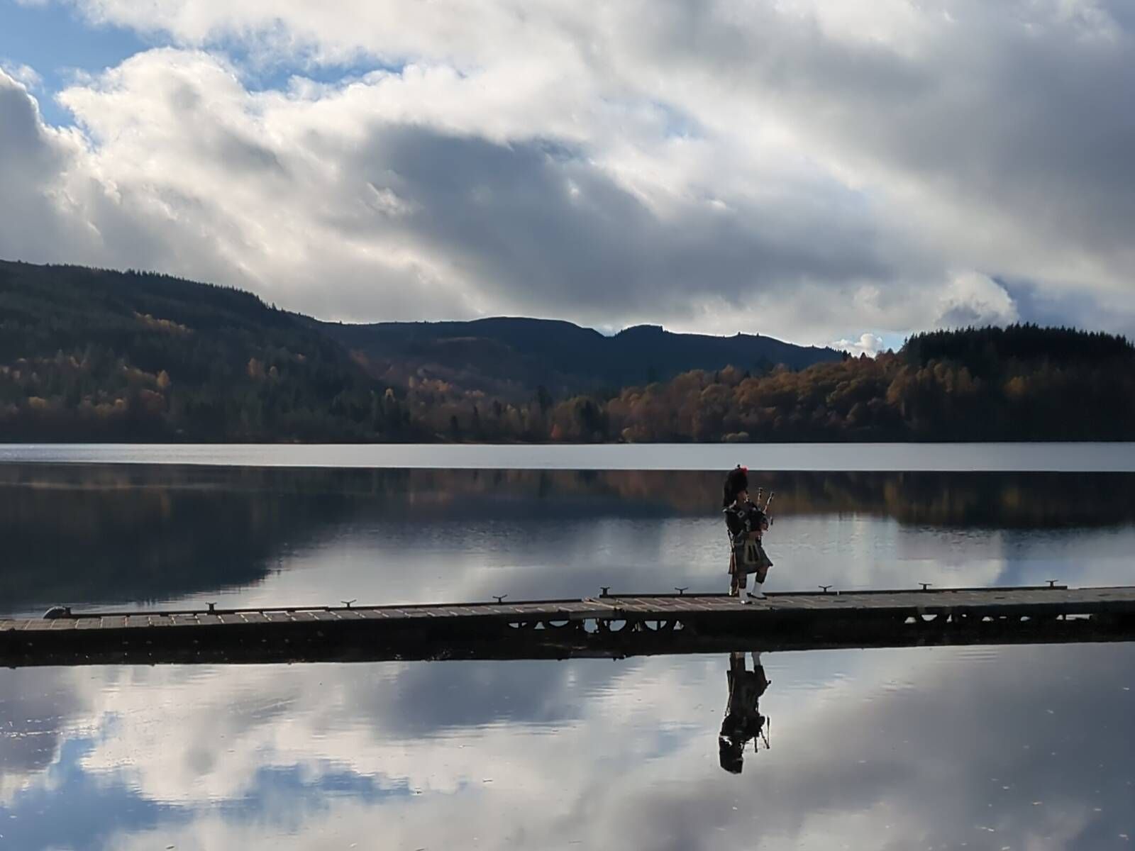 Bagpiper on jetty at loch bear Callendar, Scotland